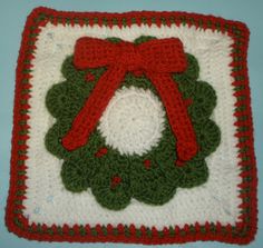 a crocheted square with a red bow on it and a green wreath in the middle