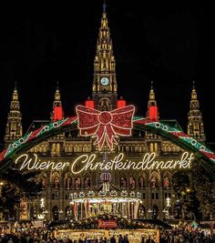 people are standing in front of a large building with christmas lights and decorations on it