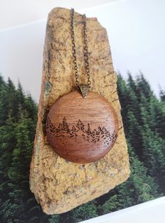 "Item: Treeline Necklace Pendant, from the Horizon Collection.  Size:  1.5\" & 2\" diameter. Material: Upcycled Walnut wood.  Adorned with an antique brass pinch bail with leaf motif and hung on a 20\" (small) OR 30\" (large) brass chain.  Custom length chains are available upon request.  Also available in Cherry & Maple. Description:  Inspired by the forests of the Boreal Shield, trees have always been a favorite muse.  This design brings the chaos and non-linear vibe to the collection. *Note: Nature-inspired Round Jewelry For Crafting, Nature-inspired Round Pendant Jewelry For Crafting, Nature-inspired Round Etched Jewelry, Rustic Round Necklace For Gift, Handmade Round Nature-inspired Necklaces, Handmade Round Nature-inspired Necklace, Rustic Handmade Round Necklace, Brown Etched Jewelry As Gift, Brown Etched Jewelry As A Gift