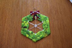 an ornament made out of green leaves on a wooden table with a red bow