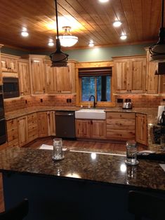 a large kitchen with wooden cabinets and granite counter tops, along with an island in the middle