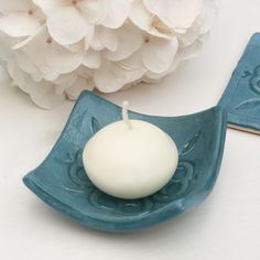 a white candle sitting on top of a blue plate