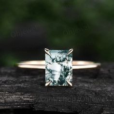 a green and white ring sitting on top of a piece of wood with trees in the background