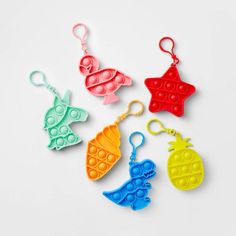 four plastic keychains with different shapes and colors on them, one is shaped like a pineapple, the other has a star