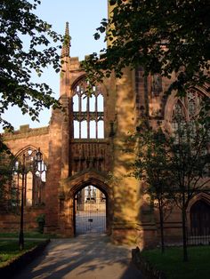 an old building with a gate in front of it and trees on the other side