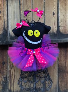 a black shirt with pink and purple polka dots on it is decorated with a monster face