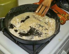 a pan filled with food cooking on top of a stove next to a green candle