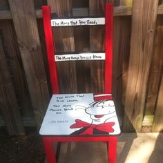 a red chair with a book on it sitting in front of a fenced area