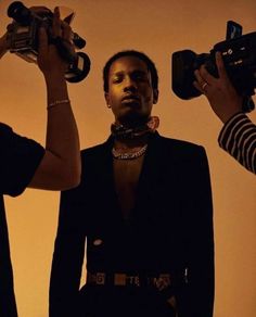 three people holding up cameras in front of their faces and one person wearing a black suit