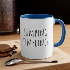 a blue and white coffee mug sitting on top of a wooden table next to a cookie