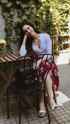 a woman sitting at a table outside with her hand on her head and looking off to the side