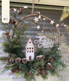 a christmas wreath with pine cones and evergreens hanging from the side of a window