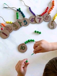 two children are doing crafts with beads and numbers on the table, while one child is holding a pencil