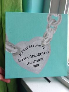 a person holding up a piece of art that says please return to alpha omicron p