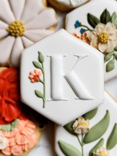 decorated cookies with the letter k on them and flowers in front of one cookie that says,'i love you '