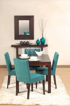 a dining room table with blue chairs and a mirror on the wall