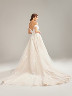 a woman in a wedding dress posing for the camera with her back to the camera