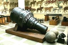 a large metal object sitting on top of a wooden stand in a room filled with other items