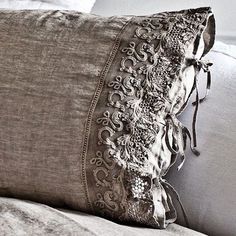 two pillows on a bed next to each other with lace trimming around the edges