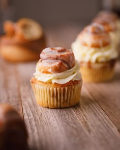 two cupcakes with frosting and cinnamon on top sitting on a wooden table