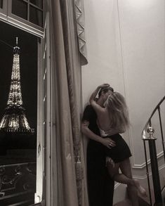 black and white photograph of two people kissing in front of the eiffel tower