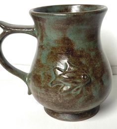 a brown and green coffee mug sitting on top of a table