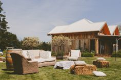 an outdoor living area with hay bales and couches in the grass near a barn