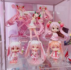 some anime figurines are on display in a glass case with other dolls behind them