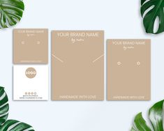 three business cards on top of a table next to green leafy plants and leaves