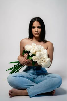 a woman sitting on the floor with flowers in her hands