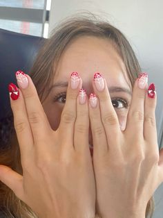 a woman with red and white nail polish holding her hands up to her face while sitting in a car