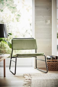 a white chair sitting on top of a hard wood floor next to a table with a lamp