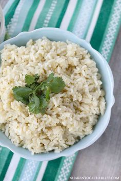 a bowl filled with rice and cilantro on top of a striped table cloth