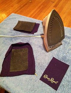 an iron and some cloths on top of a wooden floor next to a blue towel