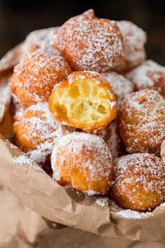 powdered sugar covered donuts in a brown paper bag