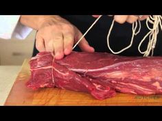 a person cutting up some meat on top of a wooden board with a string attached to it