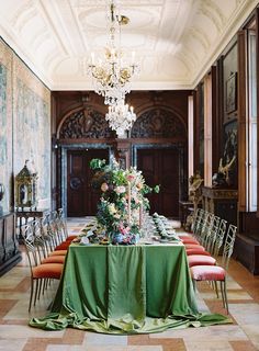 an elegant dining room with green table cloths and floral centerpiece on the long table