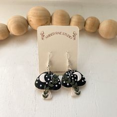 a pair of black and white earrings sitting on top of a table next to wooden beads