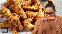 a woman is eating chicken wings and posing for the camera with her hands in front of her face