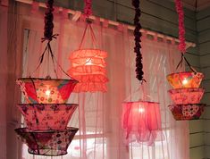 three hanging lights in front of a window with sheer curtains and pink flowers on them