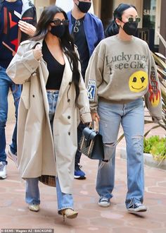 the woman is wearing a face mask while walking down the street with other people behind her