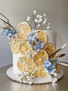 a white cake with lemon slices and blue flowers