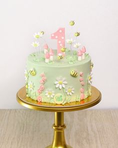 a green cake with pink and white flowers on it sitting on top of a gold plate