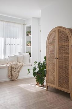 a living room with white walls and wooden furniture in front of a window filled with curtains