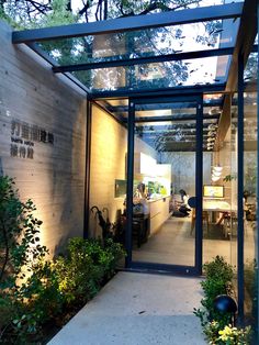 the inside of a modern house with glass walls and plants in pots on the walkway