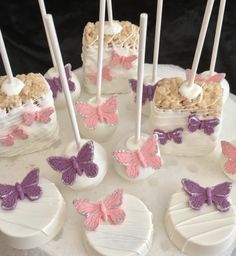 there is a cake decorated with pink and purple butterflies on the top, along with marshmallows