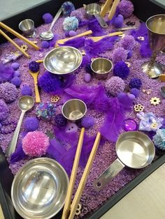 there are many spoons and bowls on the table with purple stuff around them,