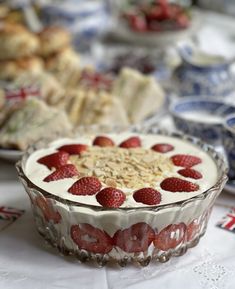 a dessert dish with strawberries in it on a table next to other plates and bowls