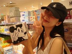 a woman is holding up a box with a mickey mouse on it in a store