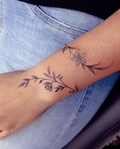 a woman's arm with a flower tattoo on the left side of her wrist